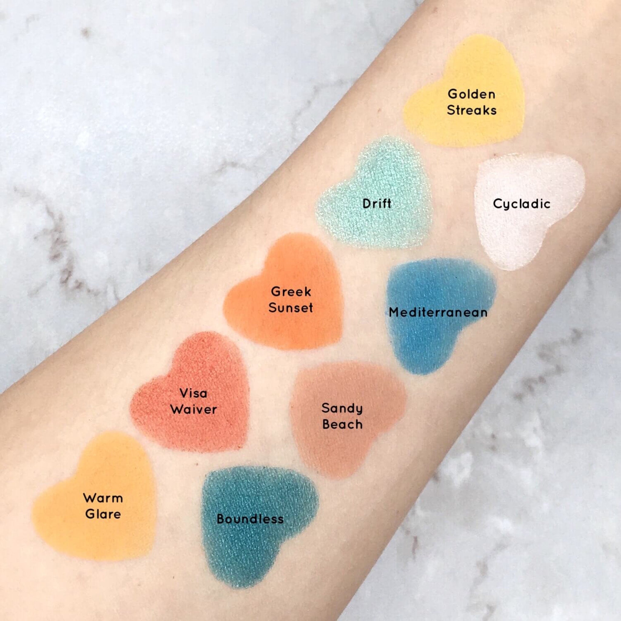 Eyeshadow swatches in heart shapes, various colors, on arm, Mavie Cosmetics