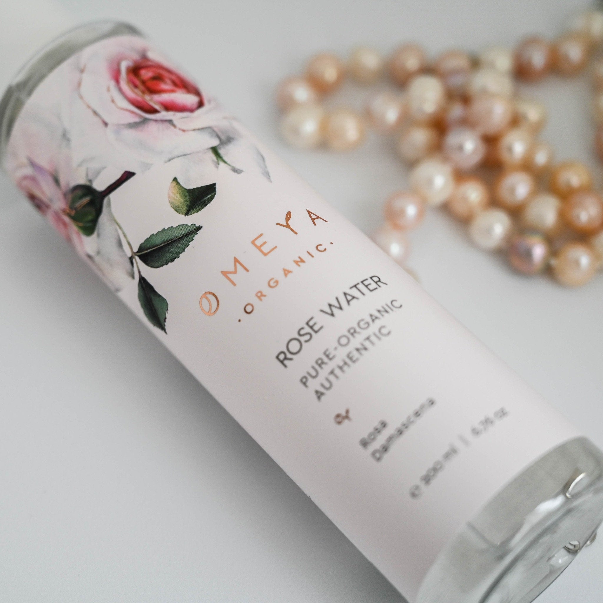 Rose water bottle with floral design, white label, and "Meya Organic" branding