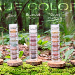 Stacked clear plastic containers with various earth-toned colors on wood slices