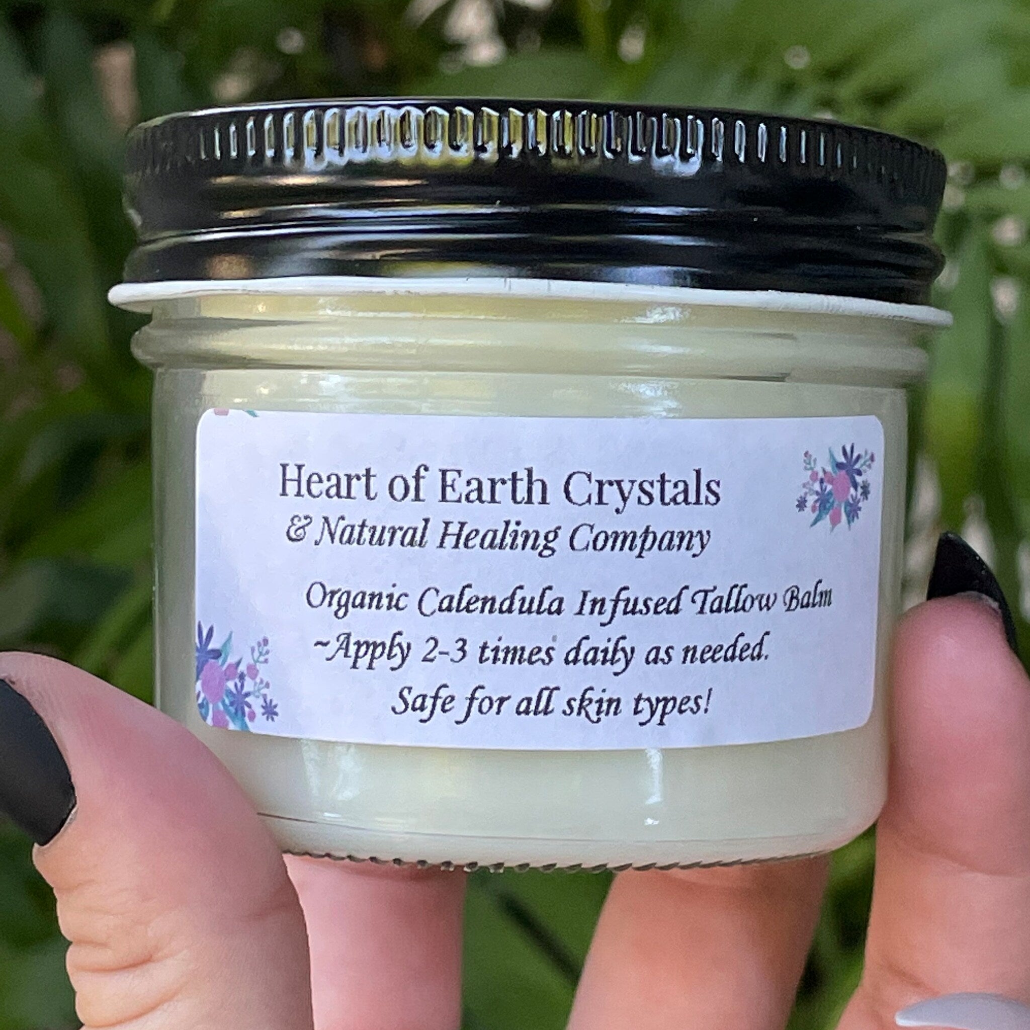 Tallow balm jar with black lid, clear glass, and Heart of Earth Crystals label