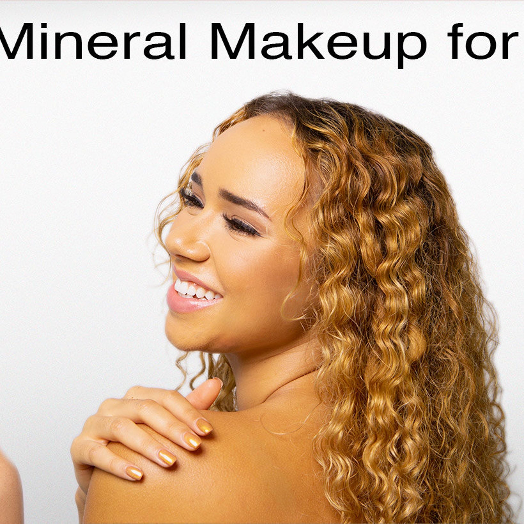 Woman with curly brown hair, smiling with gold nail polish, wearing makeup for cosmetics use
