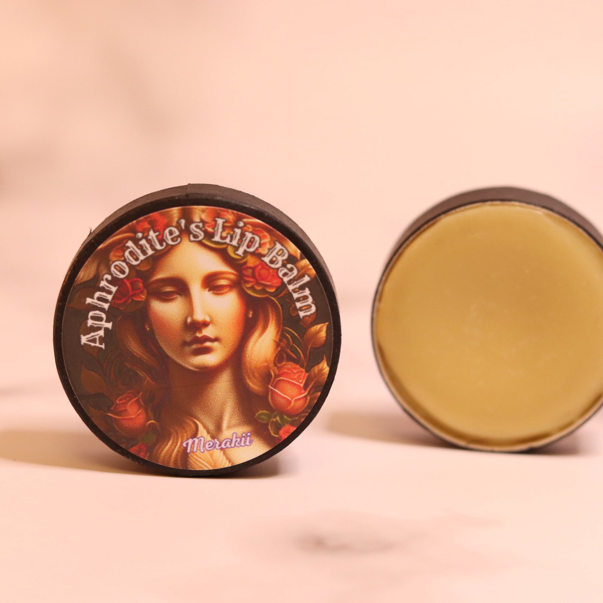 Lip balm in black round container with Aphrodite's Lip Balm text and golden balm inside