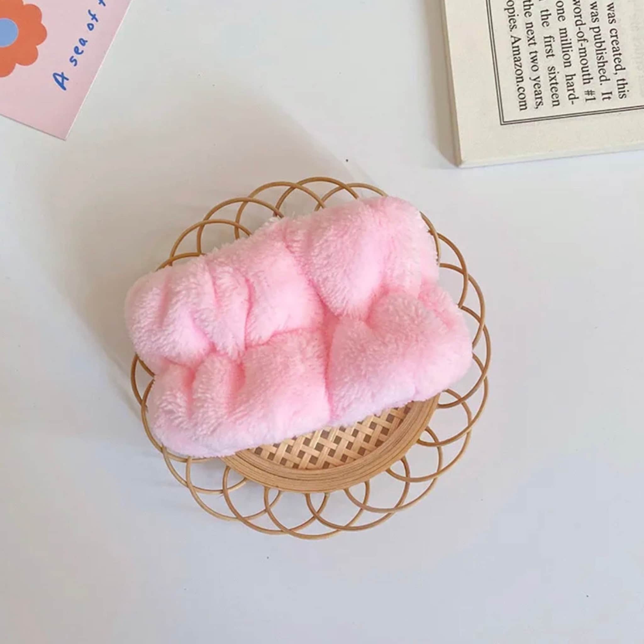 Headband pink fluffy material on woven basket, white background