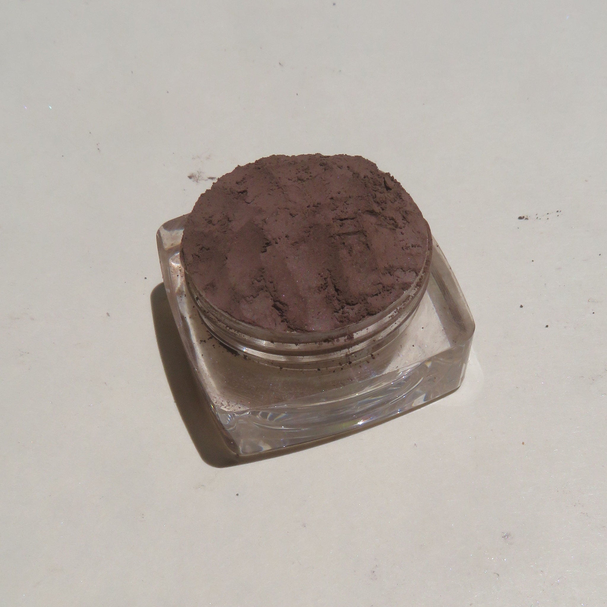 Side view of vegan loose powder eye shadow in dark brown matte finish with mineral texture