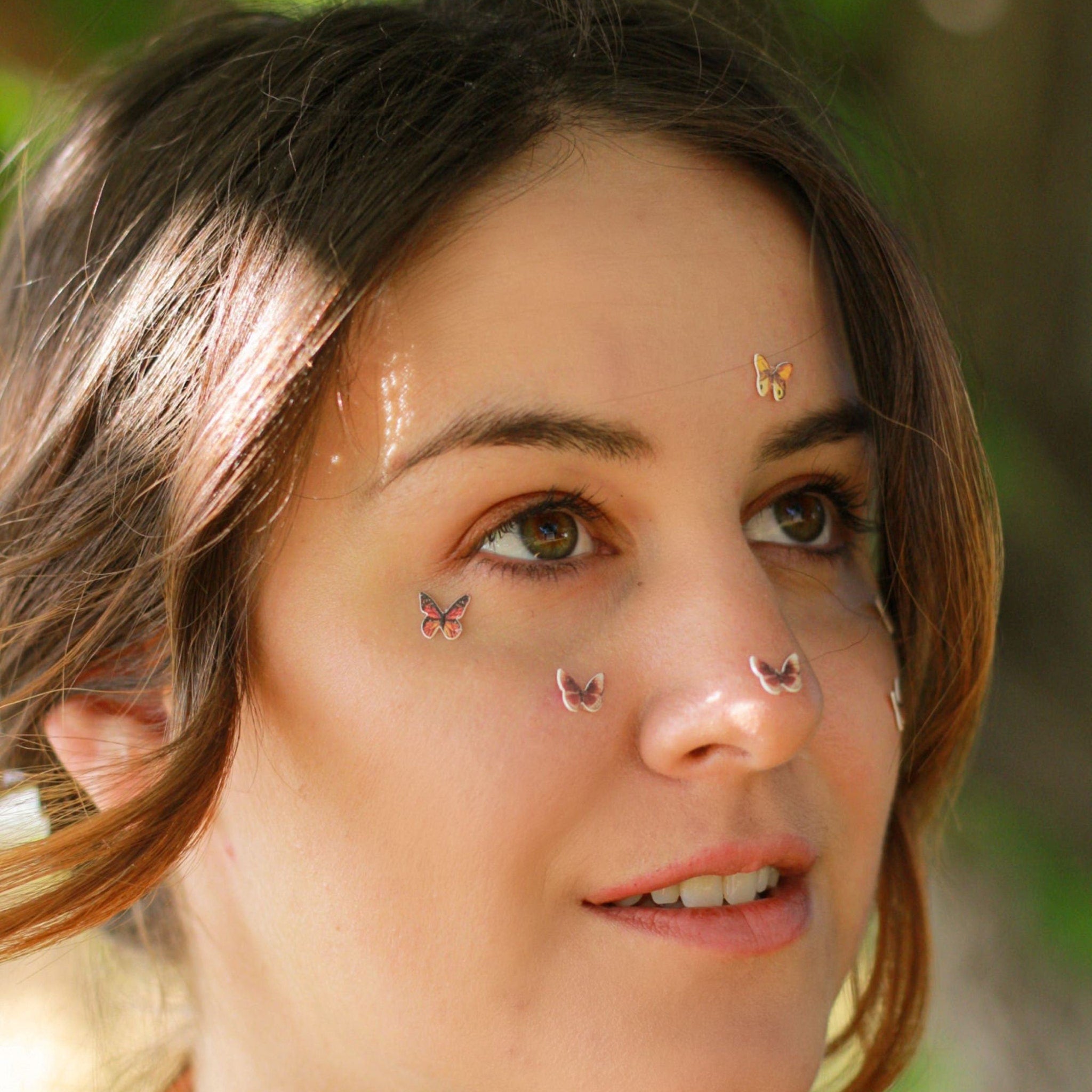 Close-up of white glitter butterfly eyeshadow decals with delicate wing details on clear adhesive backing