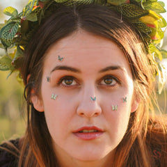 Side view of 3 white glitter butterfly eyeshadow stickers with delicate wing details on clear adhesive backing