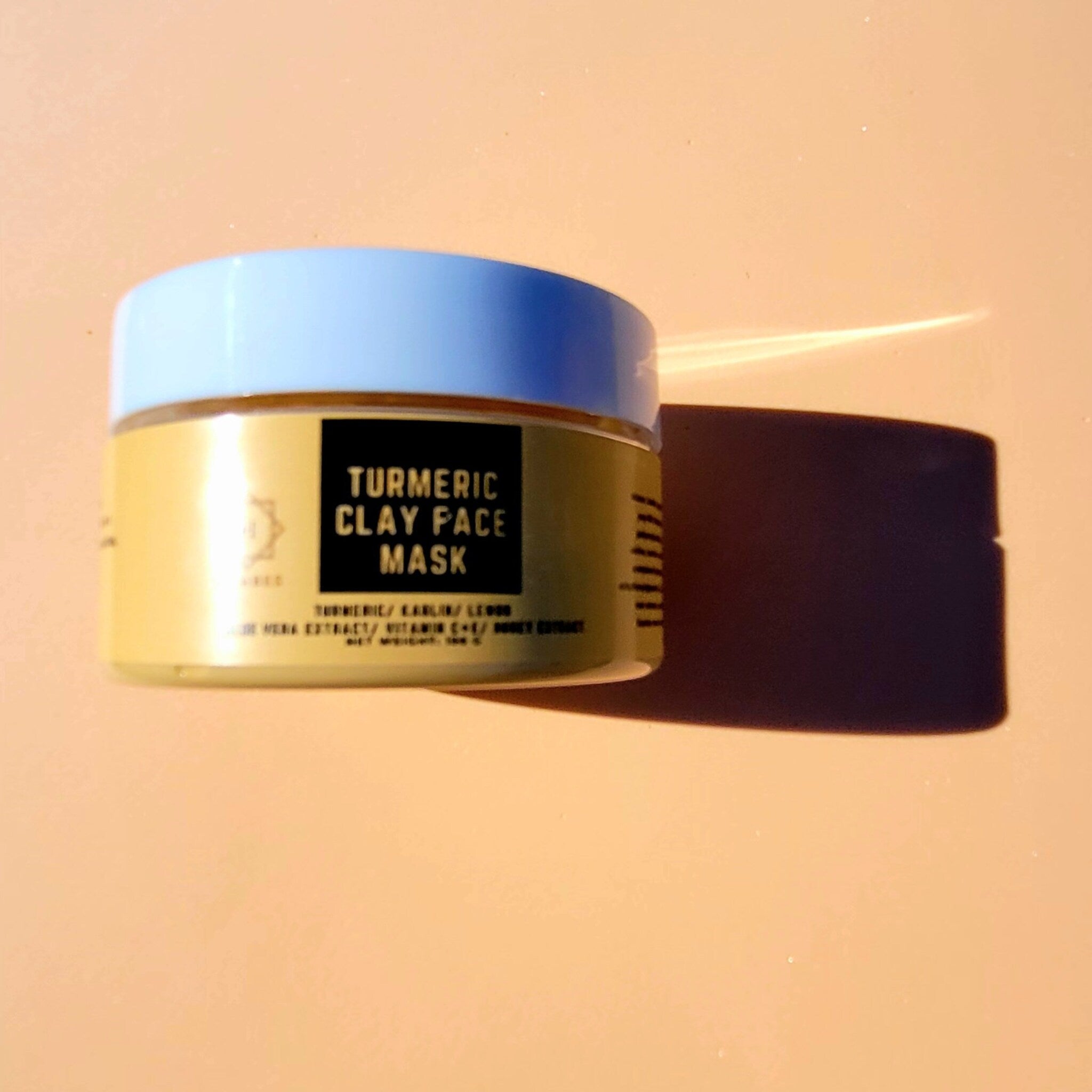Golden turmeric clay mask jar with minimalist black label, showcasing rich earthy texture inside
