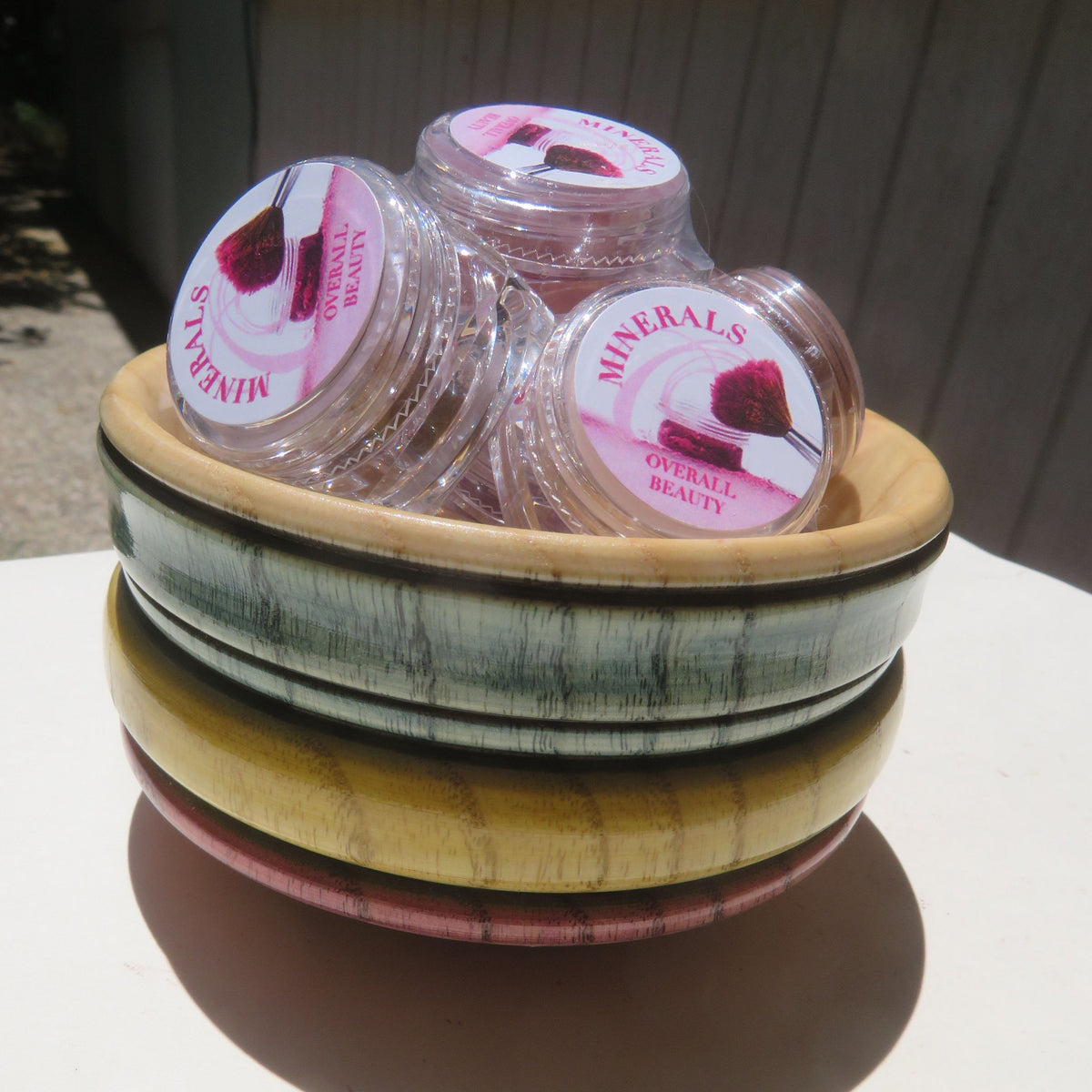 Assorted vegan mineral eye shadows and loose powder eyeliners in vibrant colors displayed in round containers with sifter lids