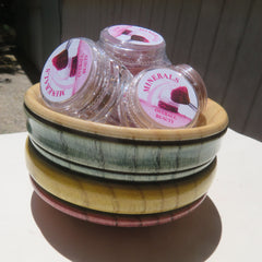 Assorted vegan mineral eye shadows and loose powder eyeliners in vibrant colors displayed in round containers with sifter lids
