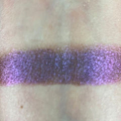 Woman applying ember-toned eye shadow with a fluffy brush for a smoky, blended look on the eyelid.