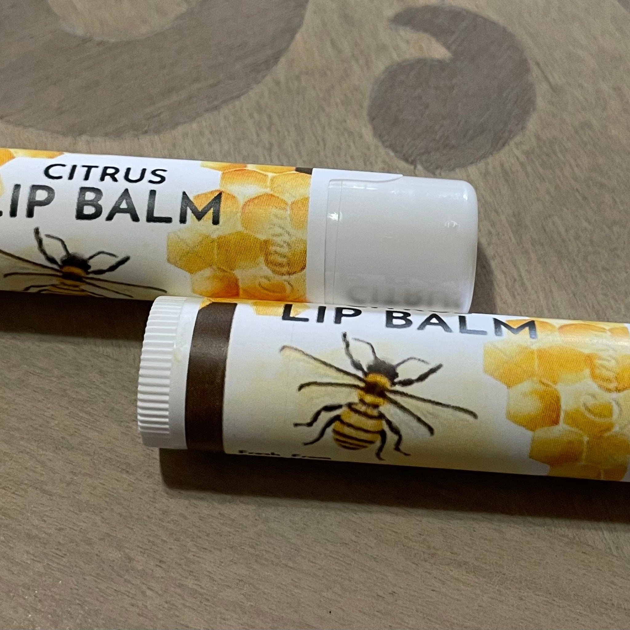 Lip balm tubes with white, brown, and yellow color scheme, featuring bee and honeycomb design, for lip care