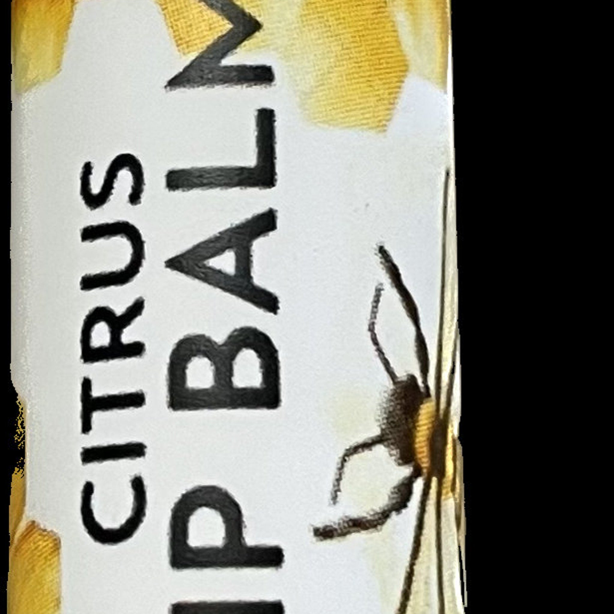 Lip balm tube with white and yellow floral pattern, black text "CITRUS LIP BALM