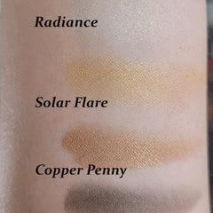 Close-up of a fingertip applying warm copper eyeshadow to eyelid, showing rich metallic pigment blend.
