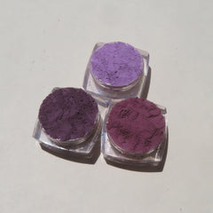 Hand applying matte purple mineral eyeshadow with brush, showcasing loose powder texture and vegan formula