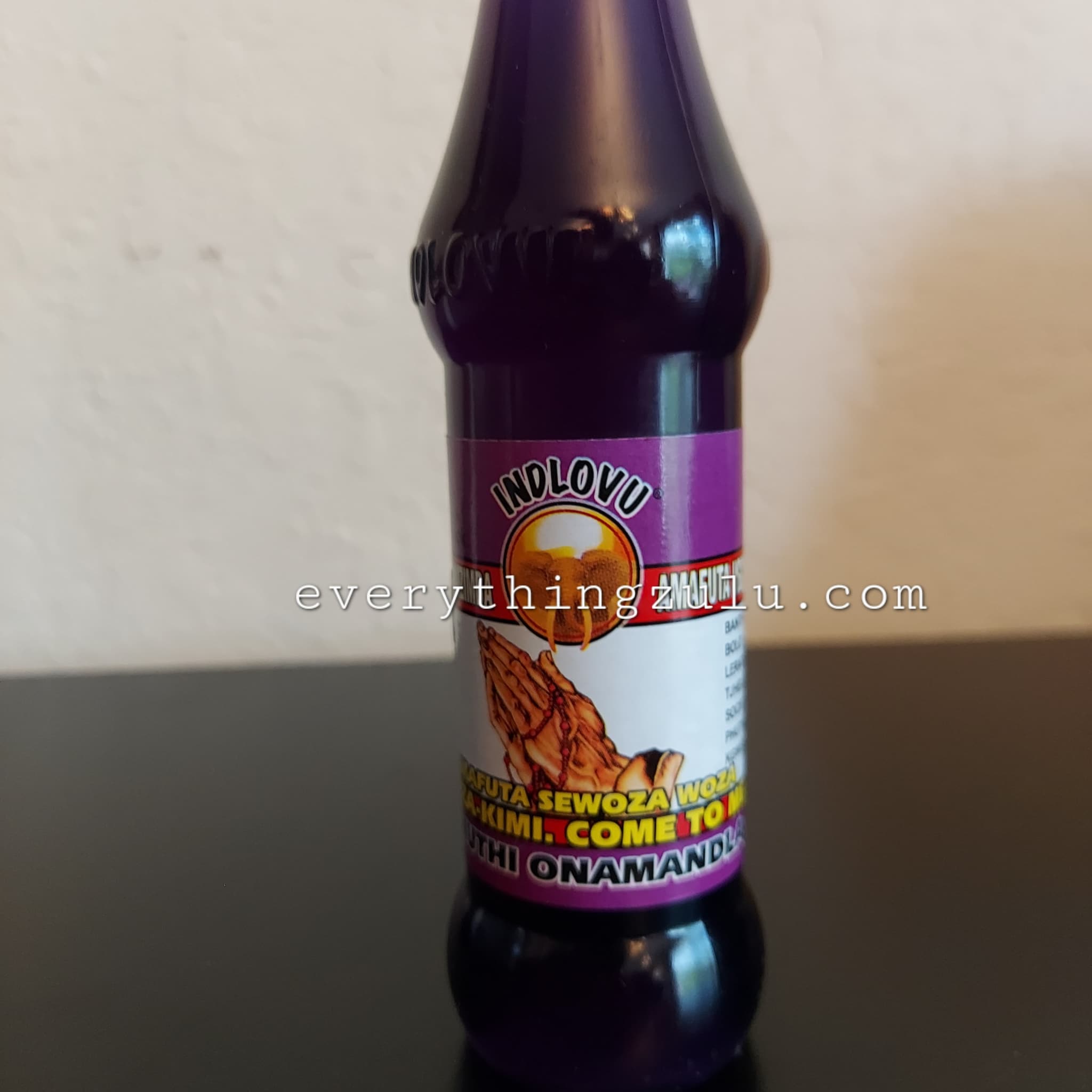 Purple bottle with INDLOVU label, white and purple label with text, sitting on a glossy surface