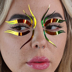 Face decals with holographic multichrome color and curved shapes applied to face for makeup look