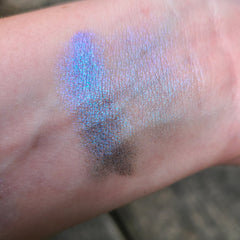 Side angle of Galaxia multichrome eyeshadow pan showcasing vibrant blue, purple, and teal shift with pink highlights
