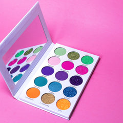 Eye makeup palette with colorful eyeshadows, white case, and mirror on pink surface