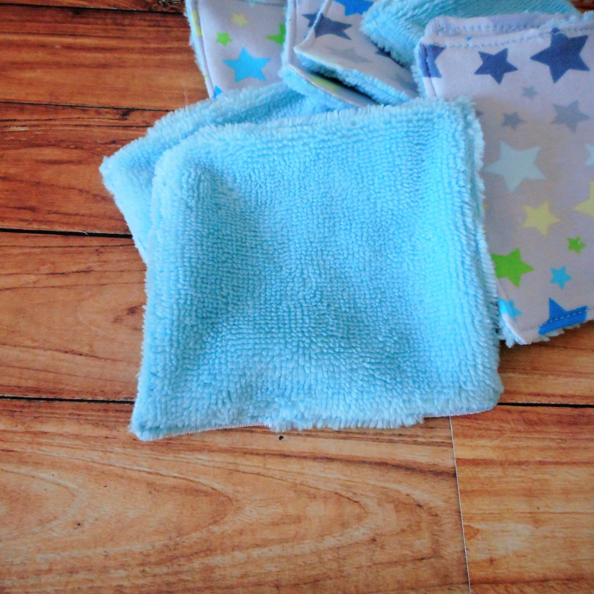 Blue terrycloth washcloths with star pattern on wooden surface