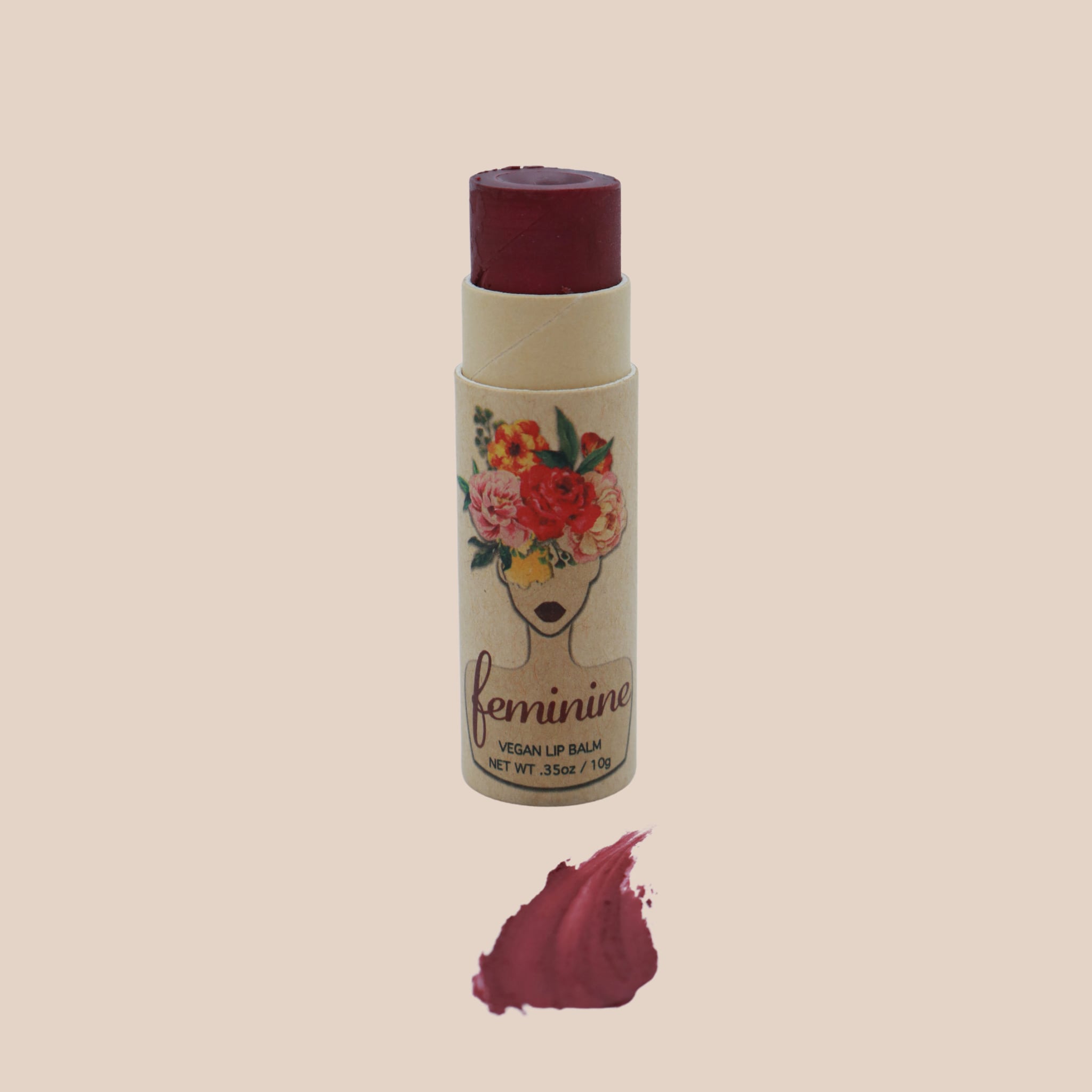 Lip balm with burgundy color, cardboard tube, and "feminine" brand text visible