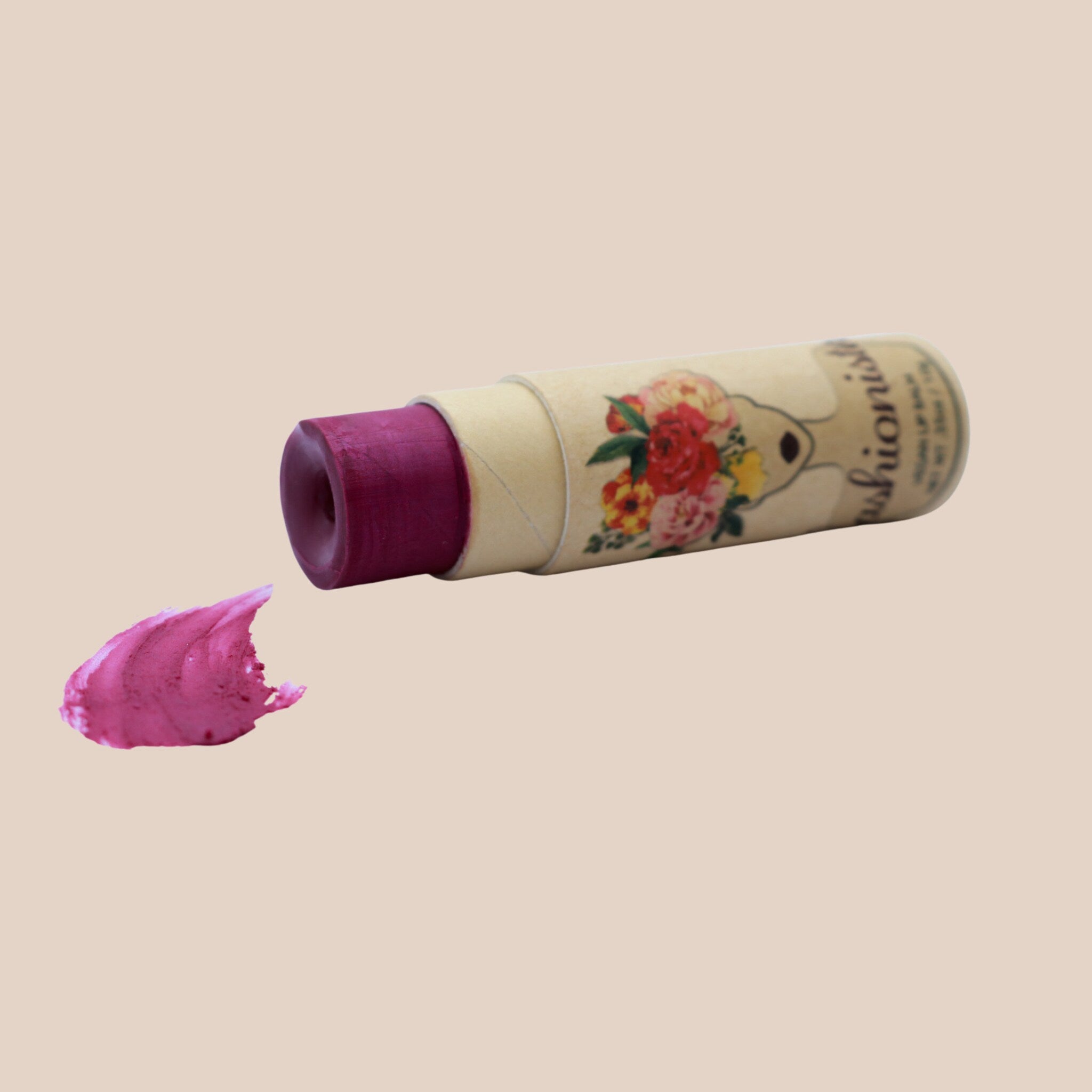 Lipstick with a burgundy color, floral pattern on the tube, and a swatch of color on a beige background