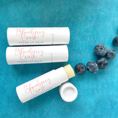 Lip balm tubes, white, with "Blueberry Crush" text, on blue background