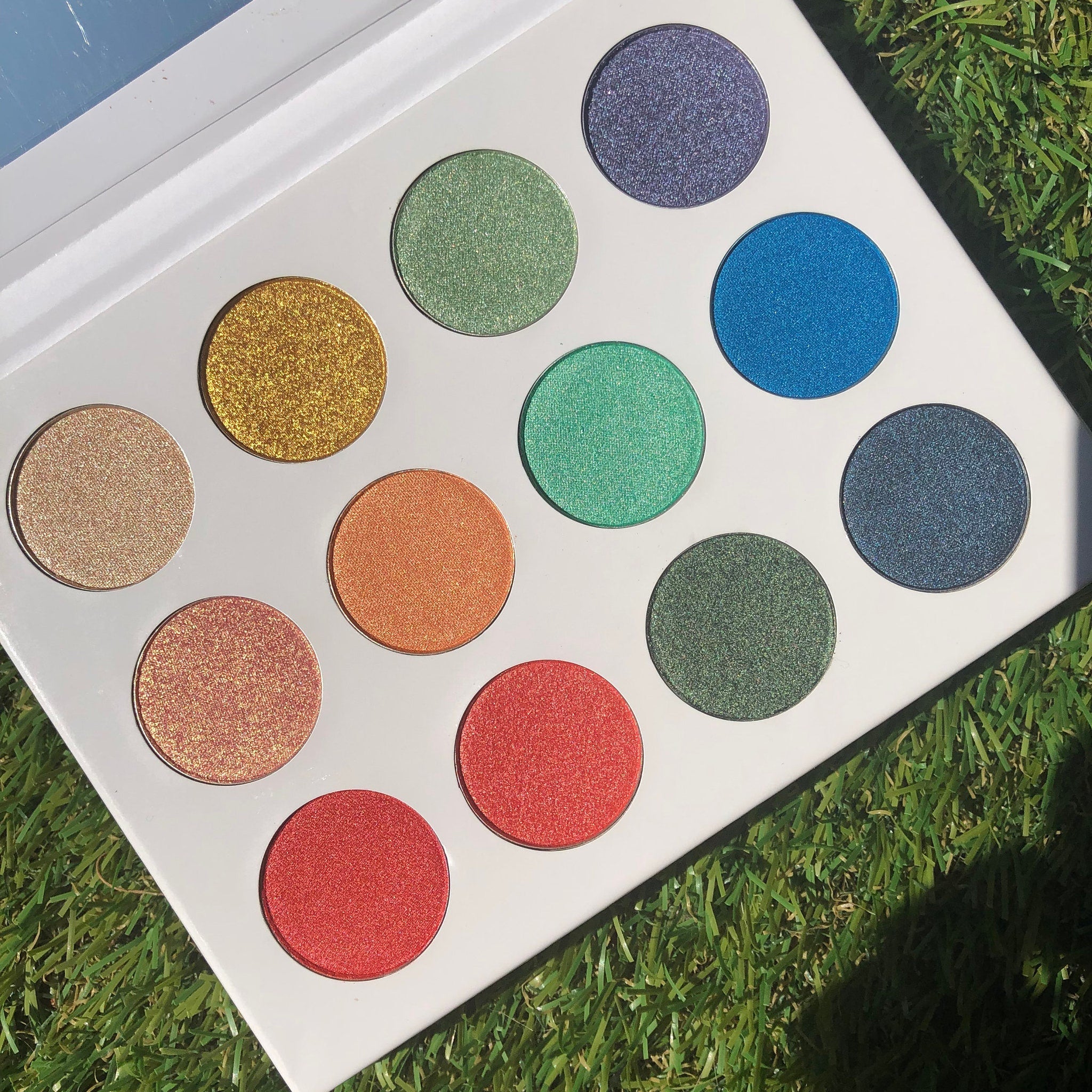 Hand applying shimmery peach eye shadow from palette with a fluffy brush