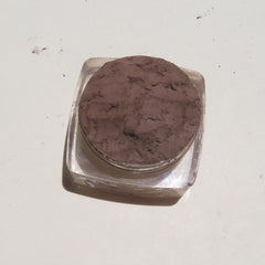Close-up of loose dark brown matte mineral eyeshadow powder with fine texture for natural eye and brow makeup