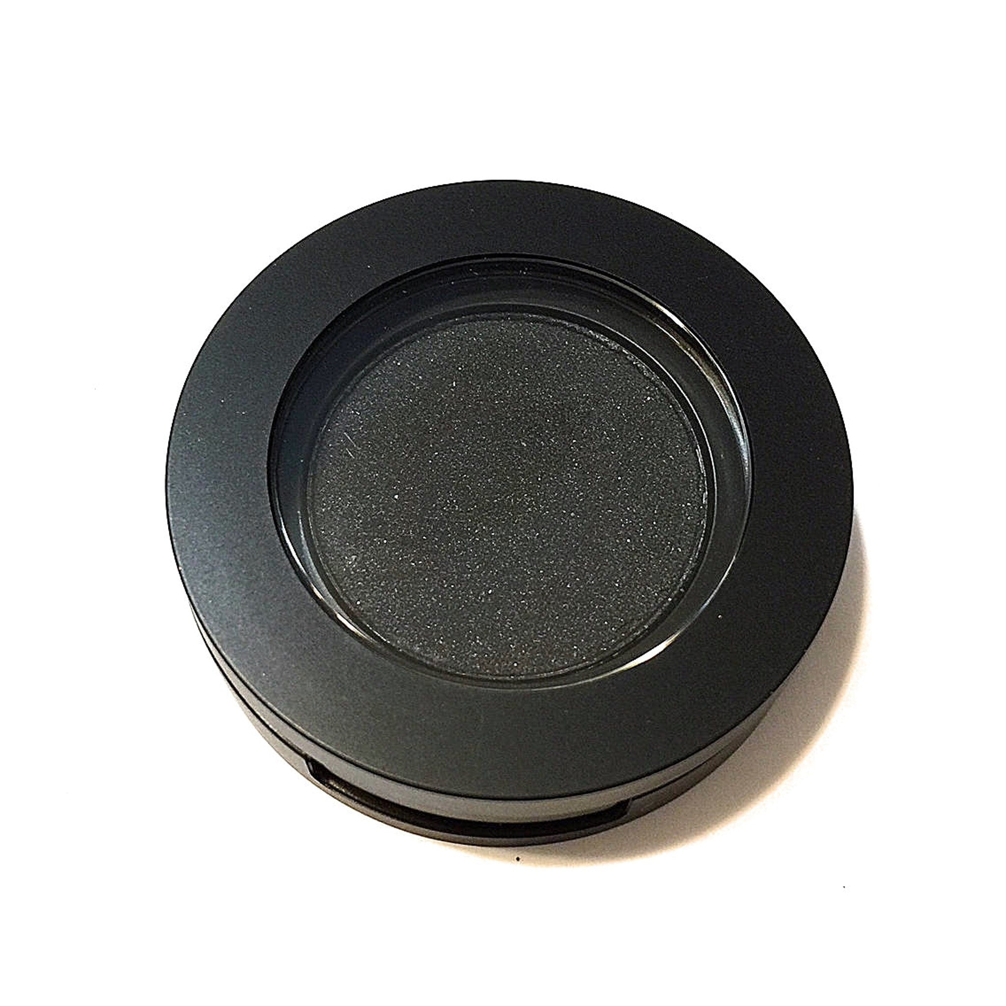 Close-up texture detail of matte black pressed mineral eyeshadow with smooth, velvety finish