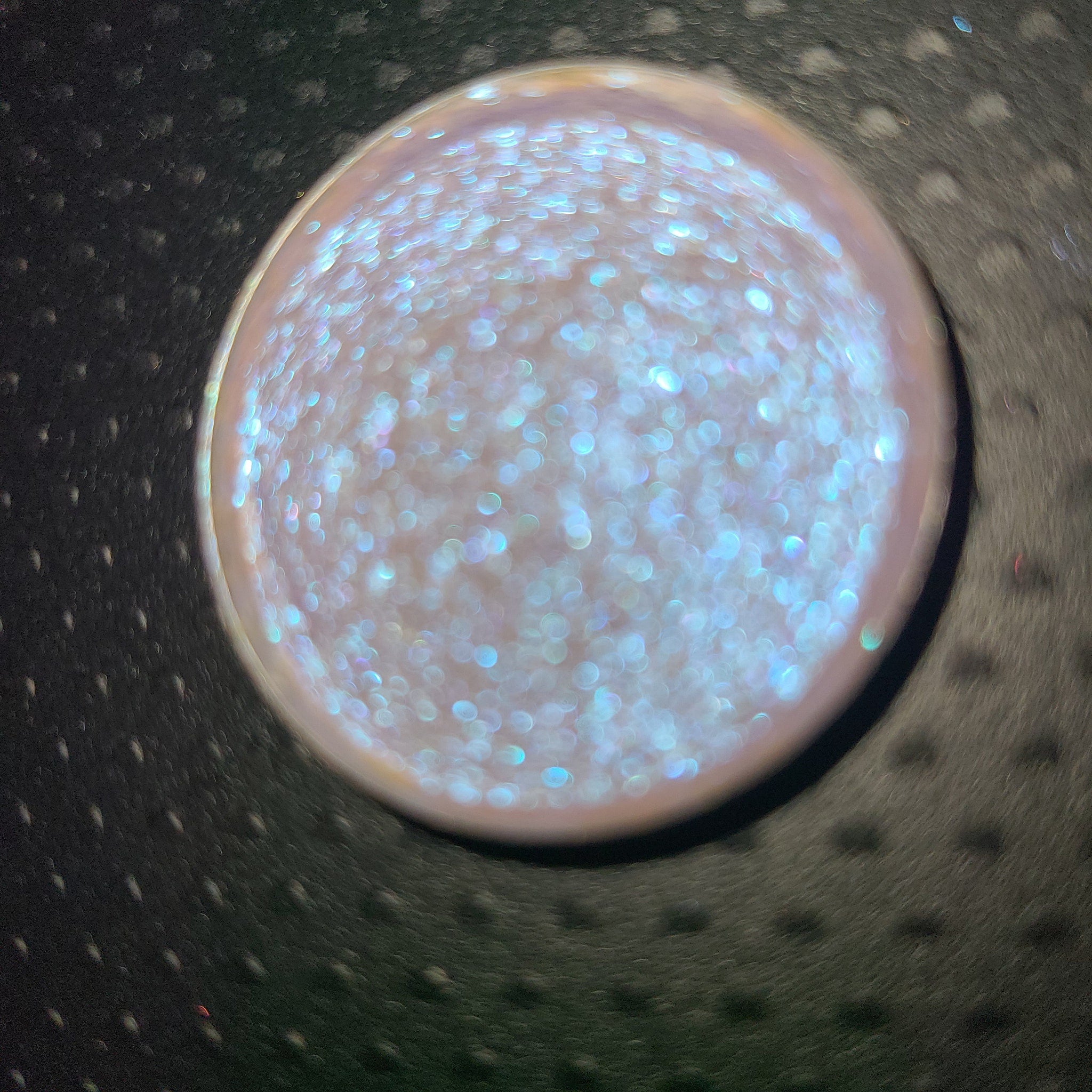 Close-up of bright blue-shifting eye shadow with sparkling particles in compact pan