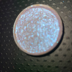 Close-up of bright blue-shifting eye shadow with sparkling particles in compact pan