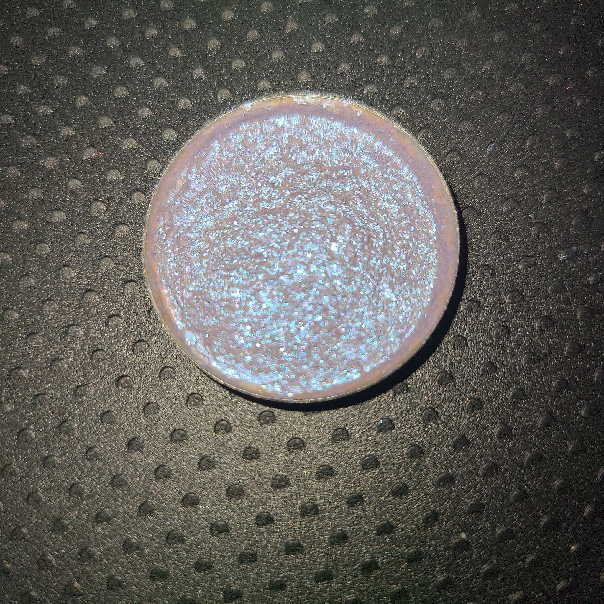 Black Lite Edit eye shadow pot with bright blue-shifting pigment and reflective highlighter, shown open on a white surface.