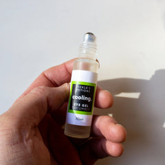 Eye gel bottle with green and white label, clear glass, held in hand by fingers, Pickle's Potions brand visible