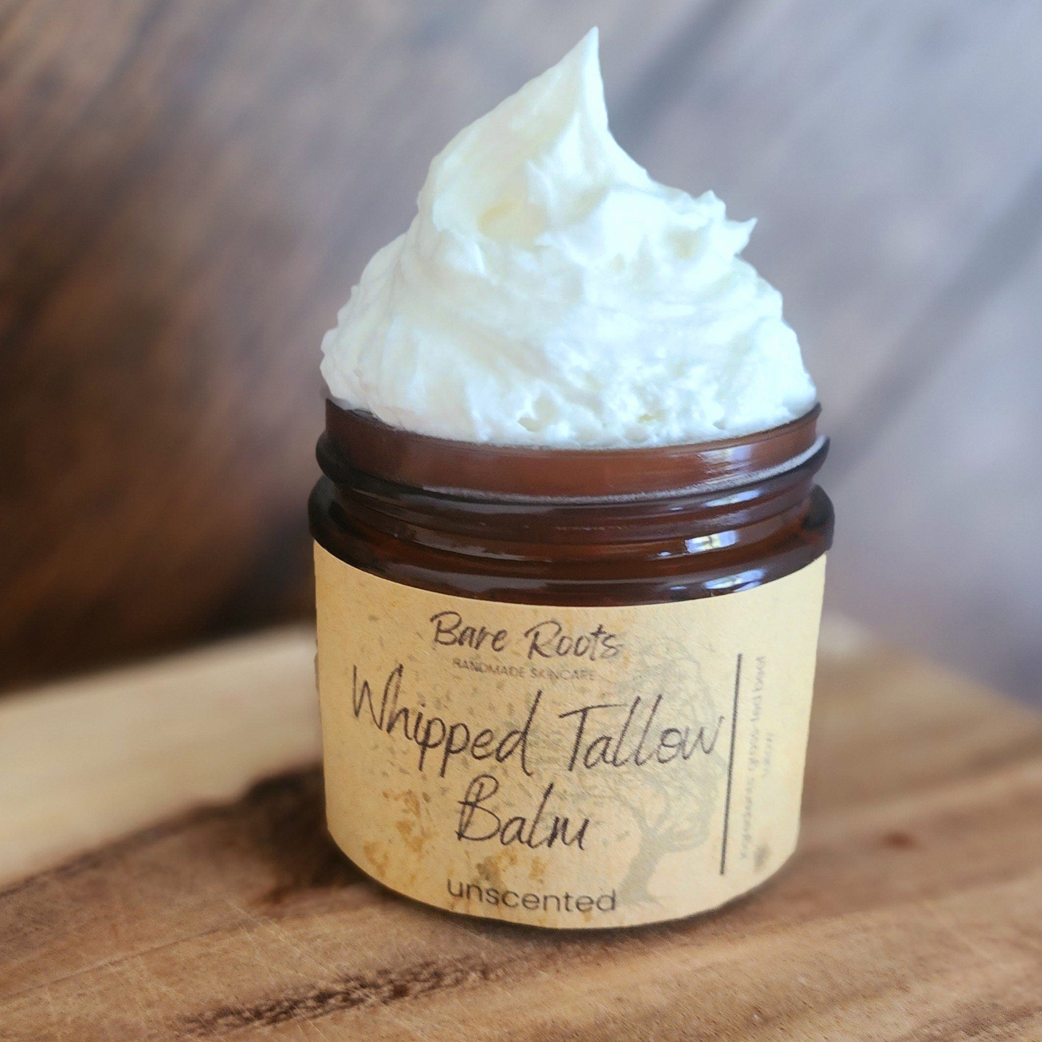 Elegant amber glass jar of whipped tallow balm with gold lid, nestled on marble surface