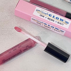 Lip gloss tube with pink liquid, black cap, and Simple Glow branding on packaging