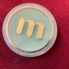 Eye makeup powder compact with gold "m" logo on green and clear plastic casing