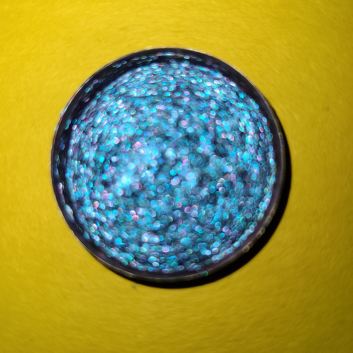 Hand-pressed multichrome eyeshadow palette with shifting blue, purple, teal, and pink metallic hues in compact case