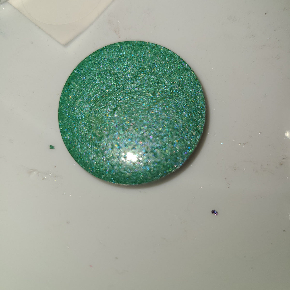 Vibrant duochrome eyeshadow pot with shifting blue-green shimmer in compact round case