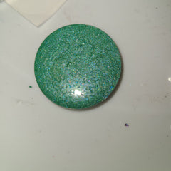 Vibrant duochrome eyeshadow pot with shifting blue-green shimmer in compact round case