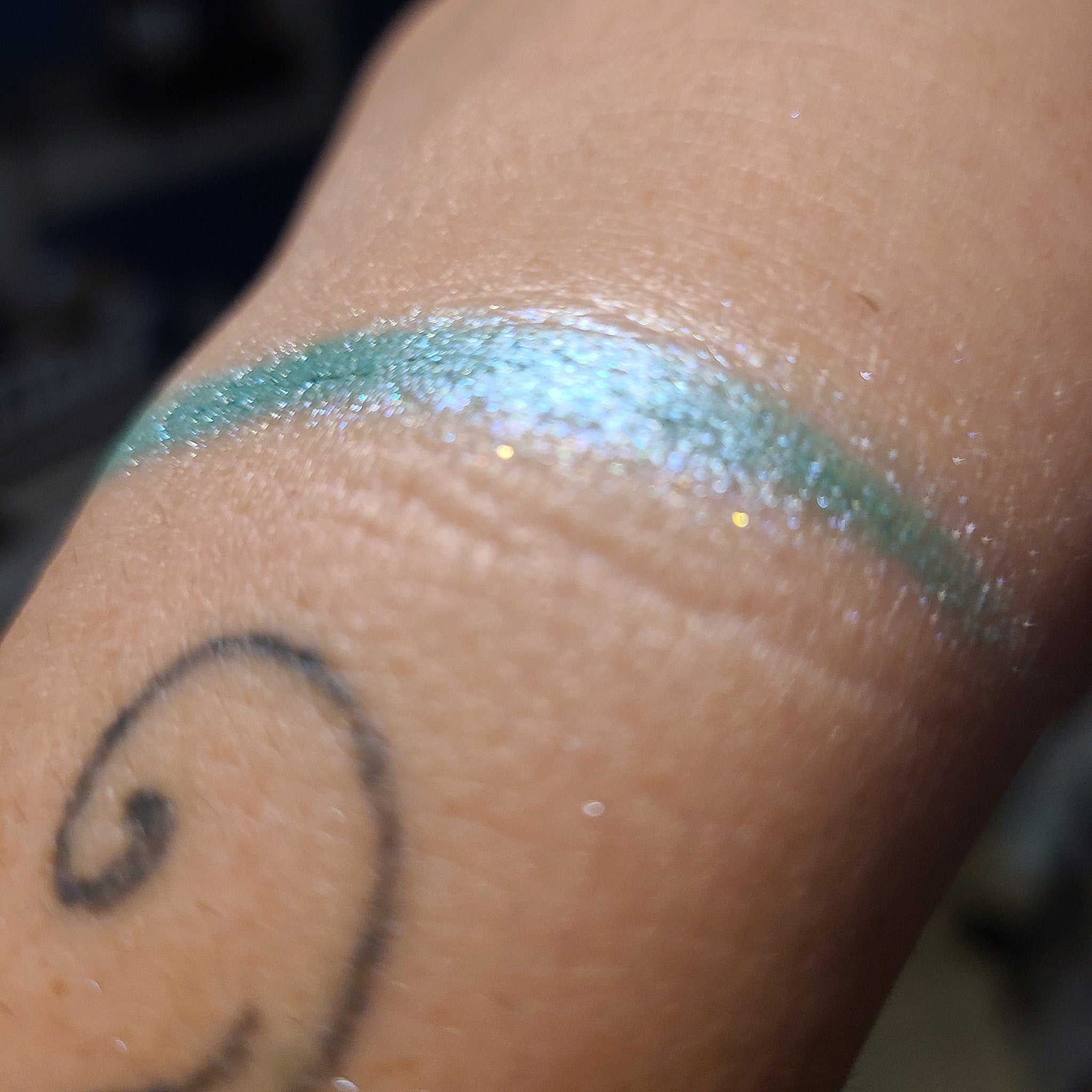 Side view of Under Da Sea Super Brite Duochrome Eyeshadow showing iridescent blue-green shift in compact case