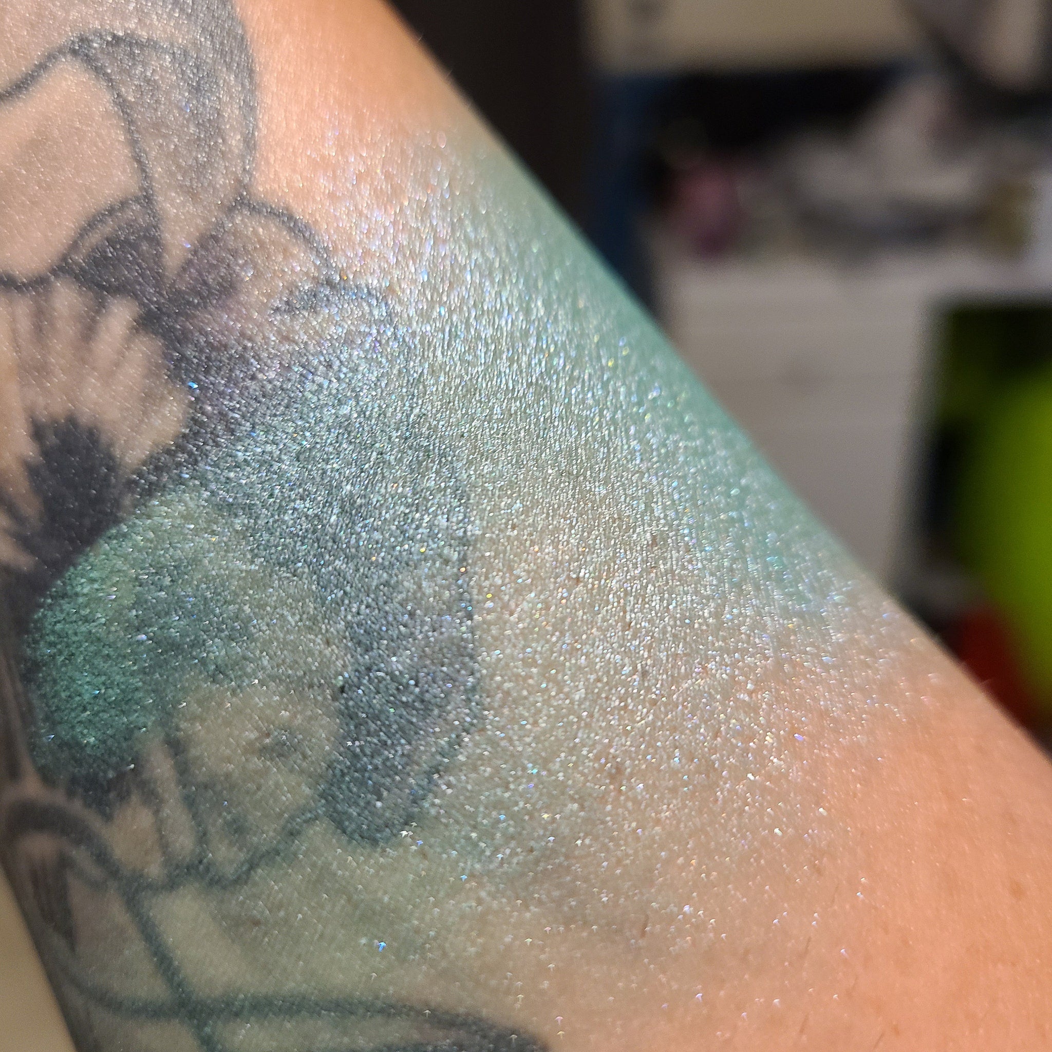 Side view of Under Da Sea Super Brite Duochrome Eyeshadow pot showing iridescent blue-green shift in compact round case