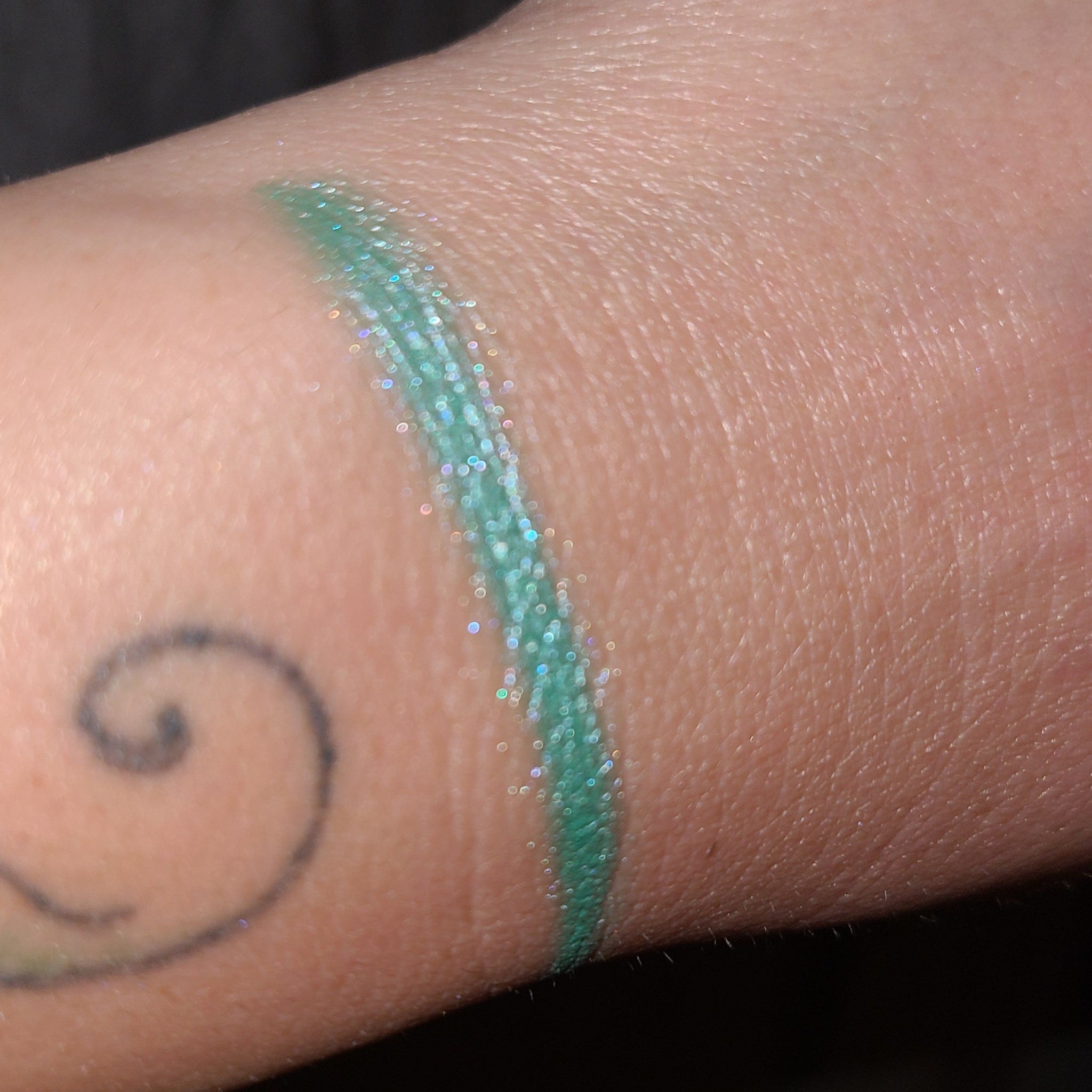 Side view of Under Da Sea Super Brite Duochrome Eyeshadow pot showing color shift from teal to purple