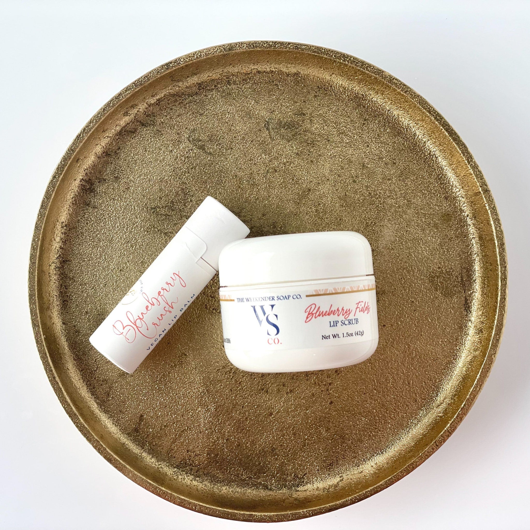 Lip balm and scrub set on gold textured tray, white containers, "Blueberry Crush" text