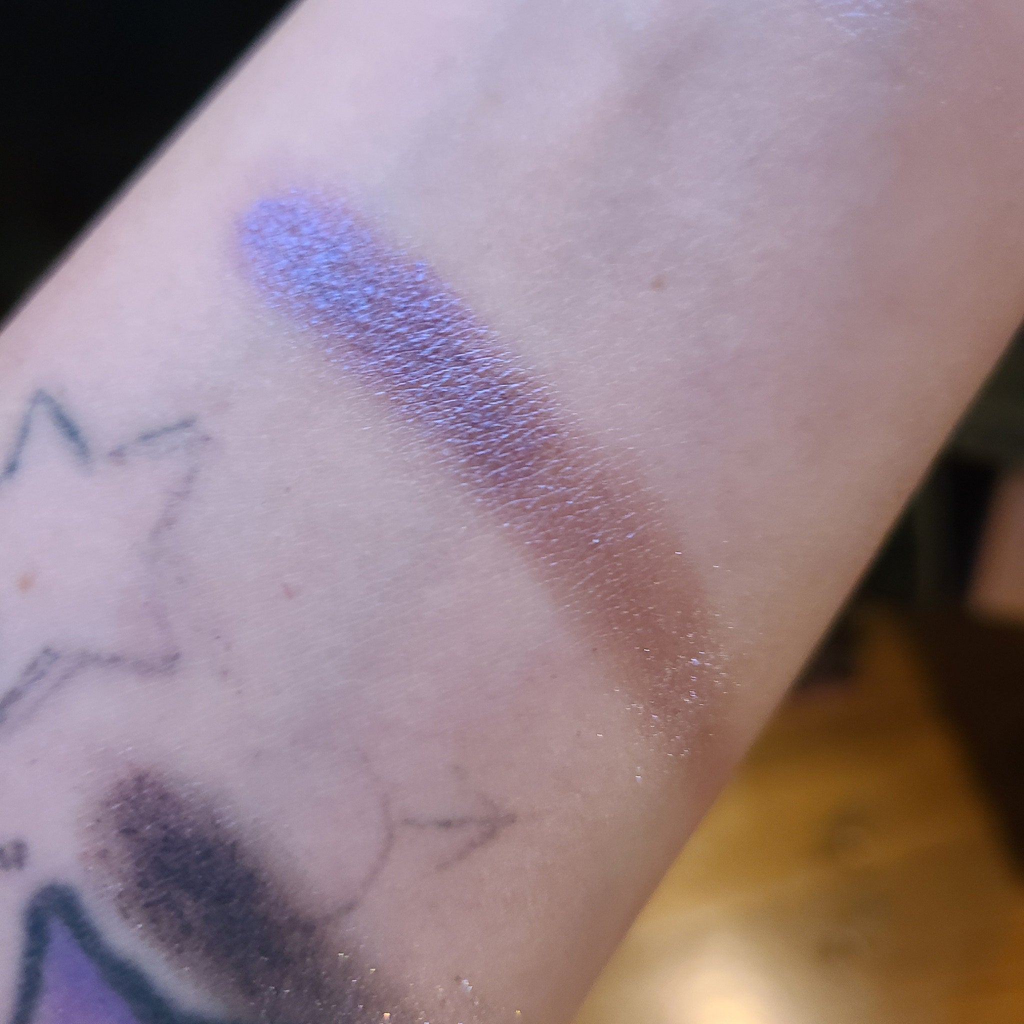Close-up of fingertips applying two purple eyeshadows—deep plum and soft lilac—to eyelid crease for gradient effect