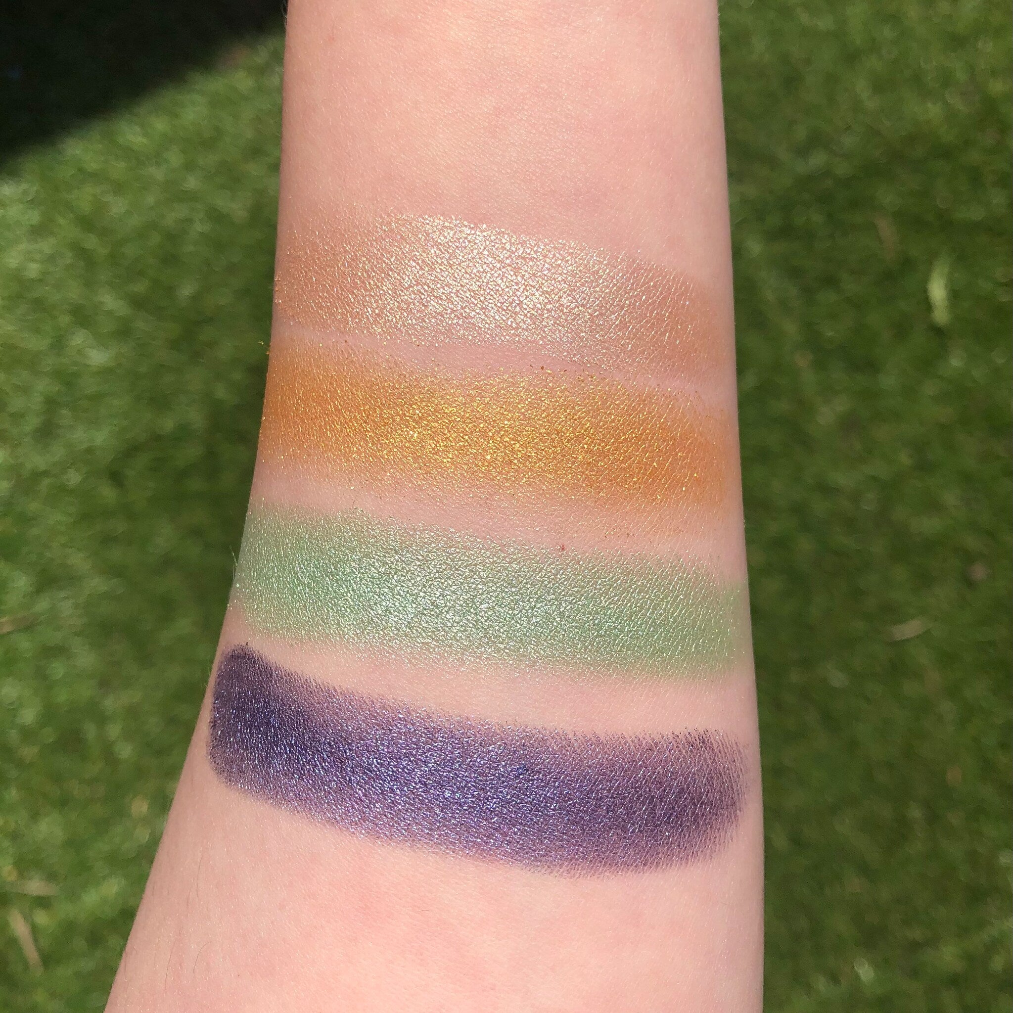 Close-up of shimmery pink and gold eye shadow pans in the Fairy Dust Palette with embossed logo