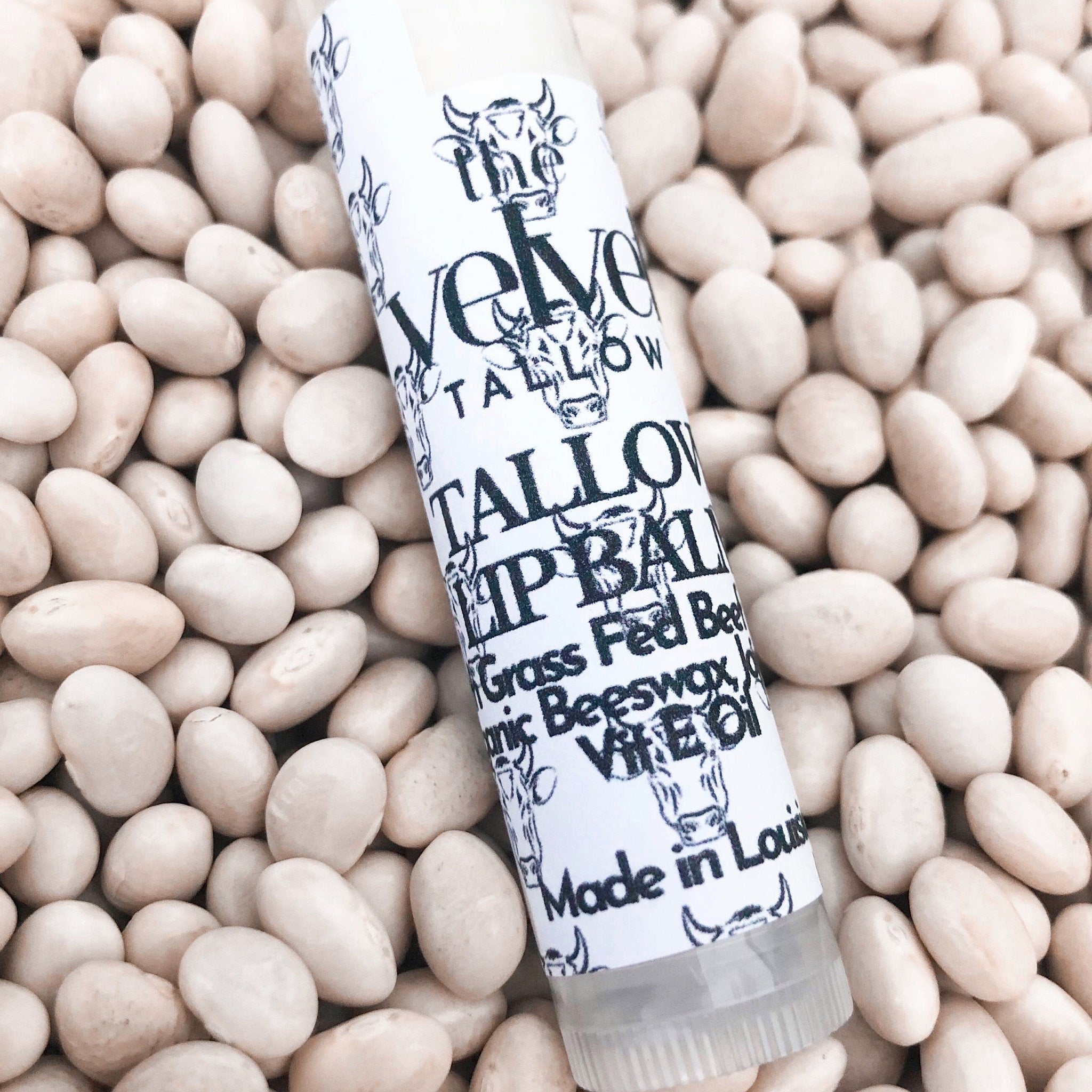 Lip balm tube with white label, black text, and white beans background