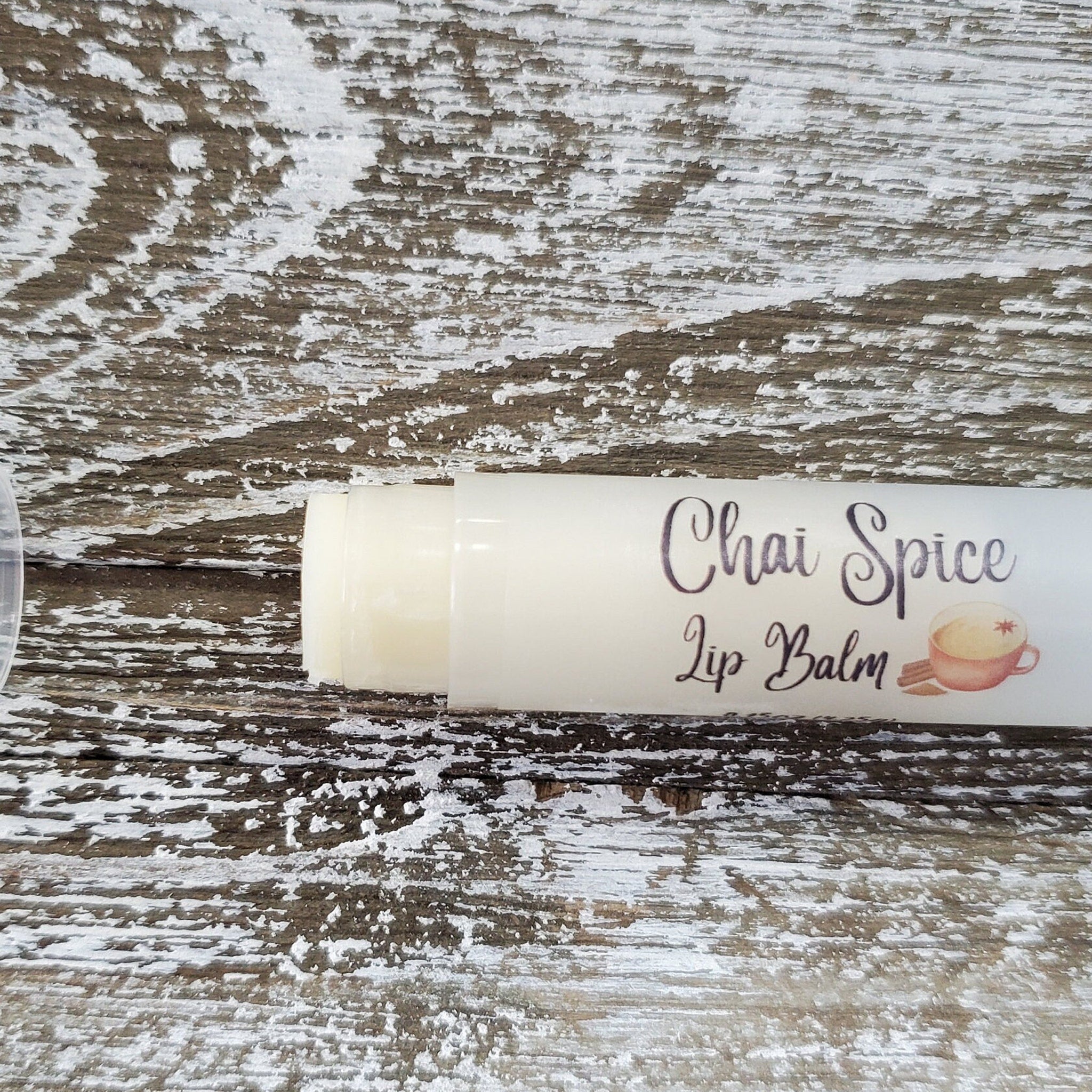 Lip balm in white tube with Chai Spice label on distressed wood background