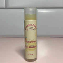 Lip butter tube with yellow liquid, beige label, and Cosmic Daisy text and logo visible