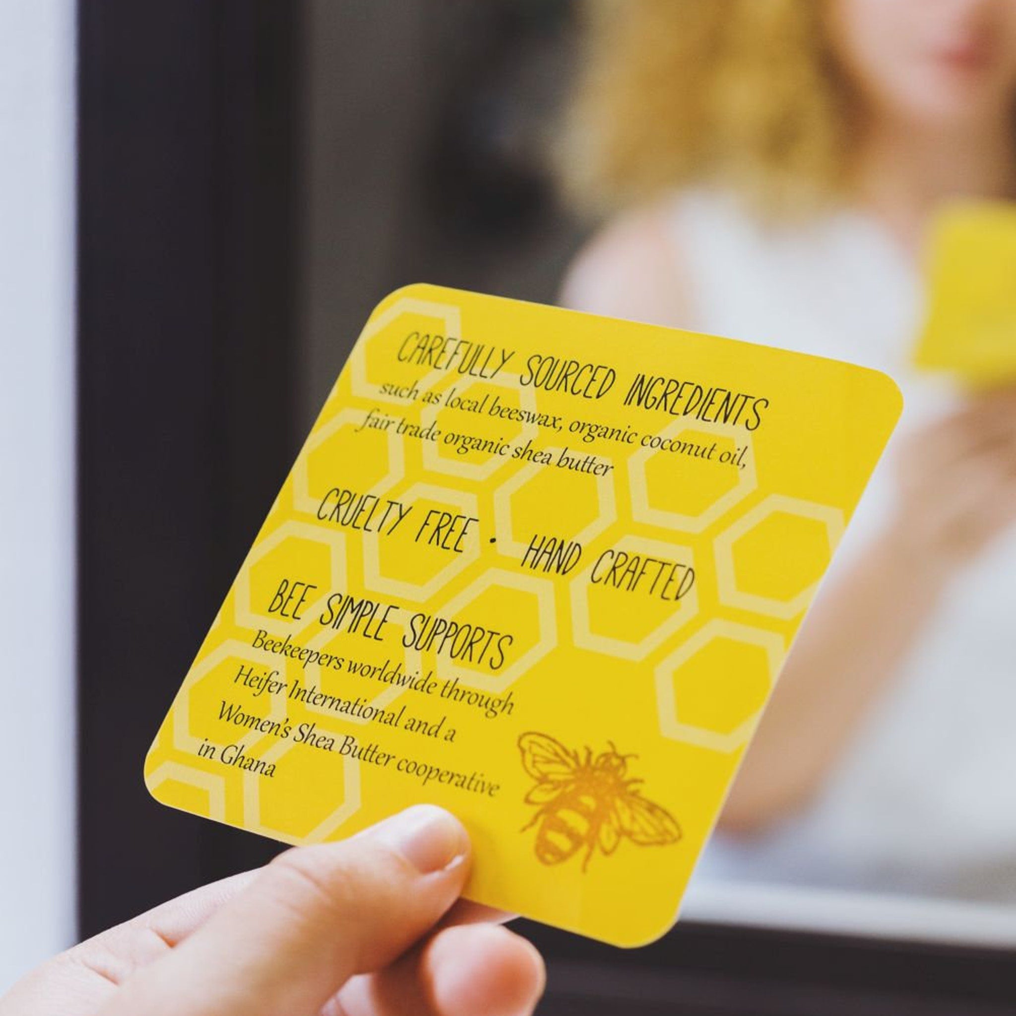 Yellow card with text, honeycomb pattern, and bee graphic held by hand, Bee Simple brand