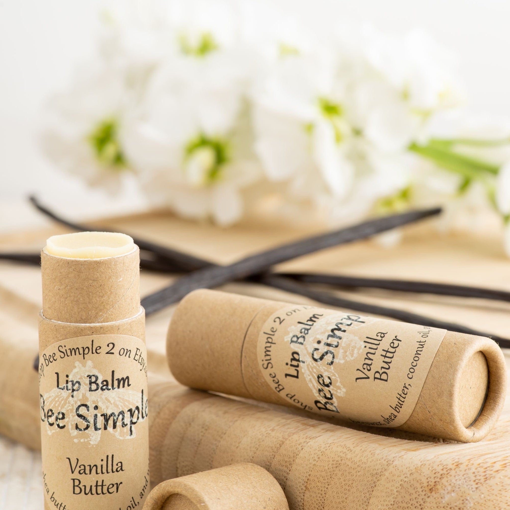 Lip balm tubes with beige paper and Bee Simple label, vanilla butter flavor, on wooden surface